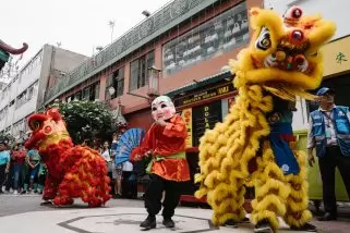 Đoàn lân sư rồng tại Hoàng Mai Hà Nội 1 Colorful lion dance parade with performers in traditional costumes celebrating cultural festival on busy city street.